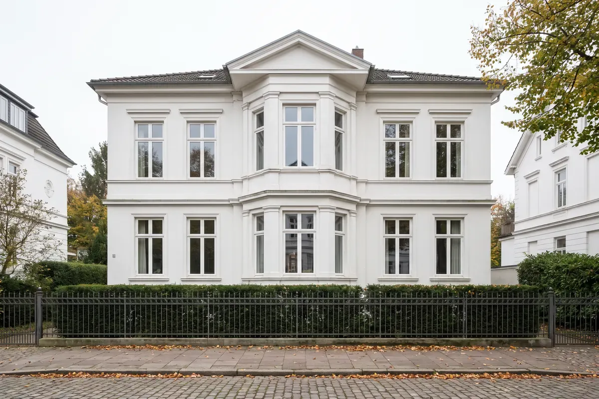 Weiße Stadtvilla mit Mittelrisalit, Ziergitter und Hecke
